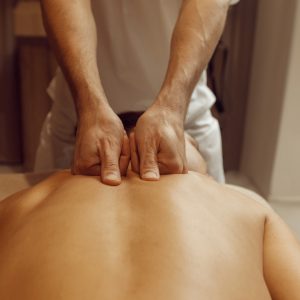 Male masseur rubbing back to slim woman, massage